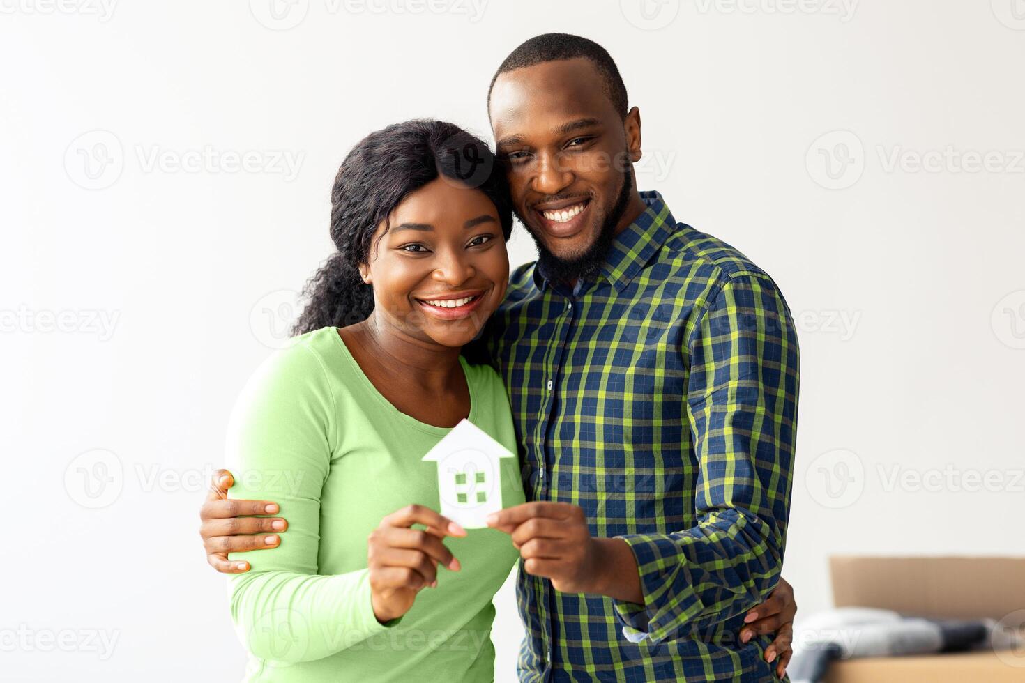 Family Housing Concept. Joyful Black Couple Holding Paper House Figure In Hands, Happy Millennial African American Spouses Enjoying Relocation Or Celebrating Buying New Property, Copy Space photo
