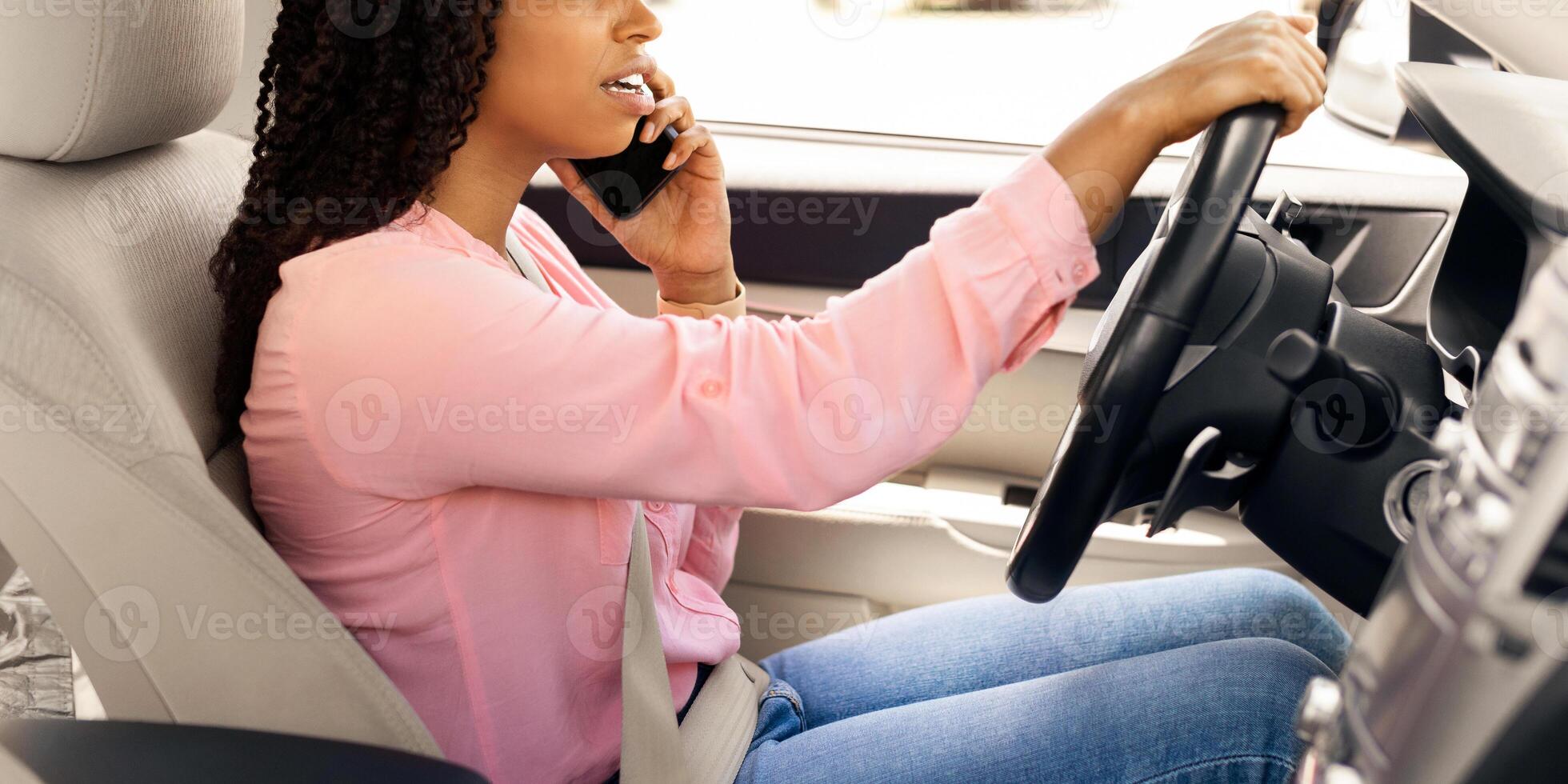 Portait of serious African American woman talking on mobile phone while driving car, unwary female driver using her cellphone, profile side view of unhappy lady arguing and riding in the city photo