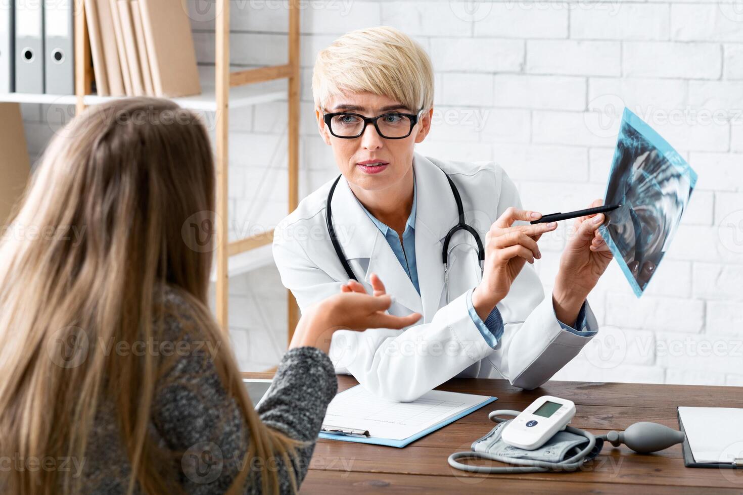 Conversation with patient. Woman dentist explains to patient problem in interior of office photo