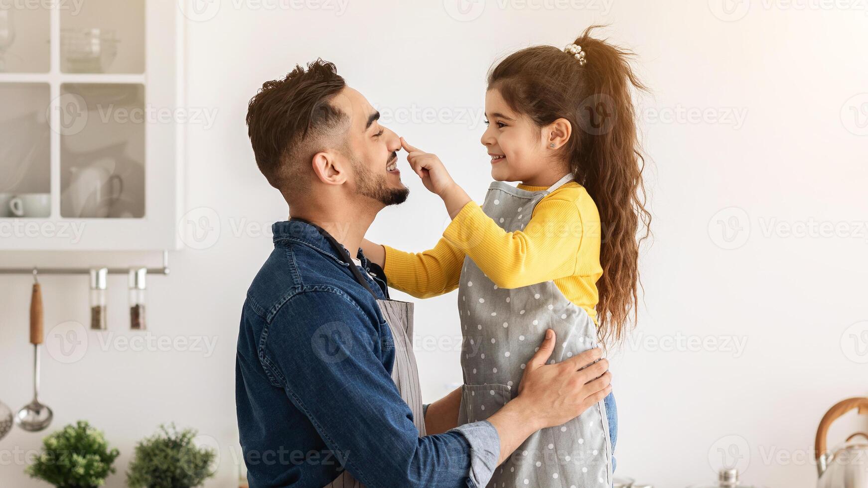 Happy Middle Eastern Dad And Little Daughter Having Fun While Baking Cookies In Kitchen Together, Cute Female Child Playfully Touching Father's Nose And Laughing, Enjoying Spending Time With Daddy photo