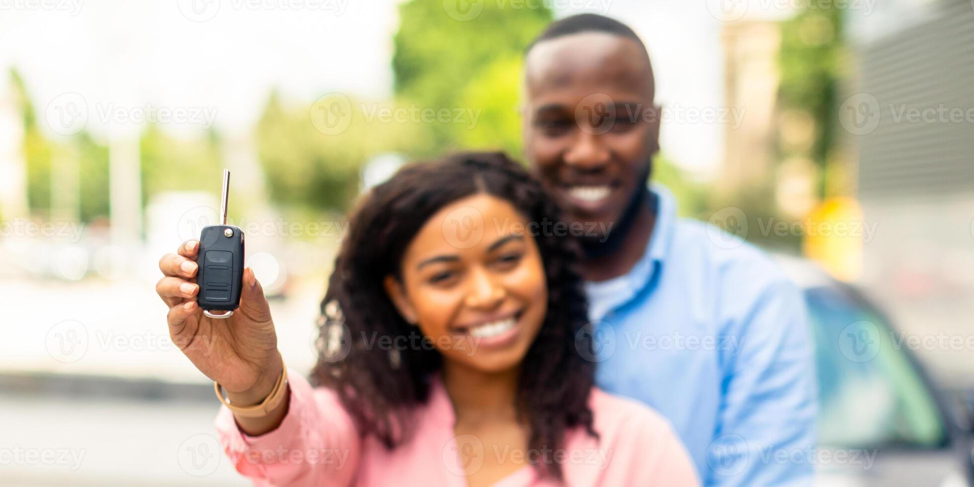 Buying New Car. Happy Black Woman Showing Keys Of Her Automobile, Man Embracing His Wife, Using Auto Rental Service, Lady Celebrating Receiving Drivers License, Smiling And Looking At Camera photo