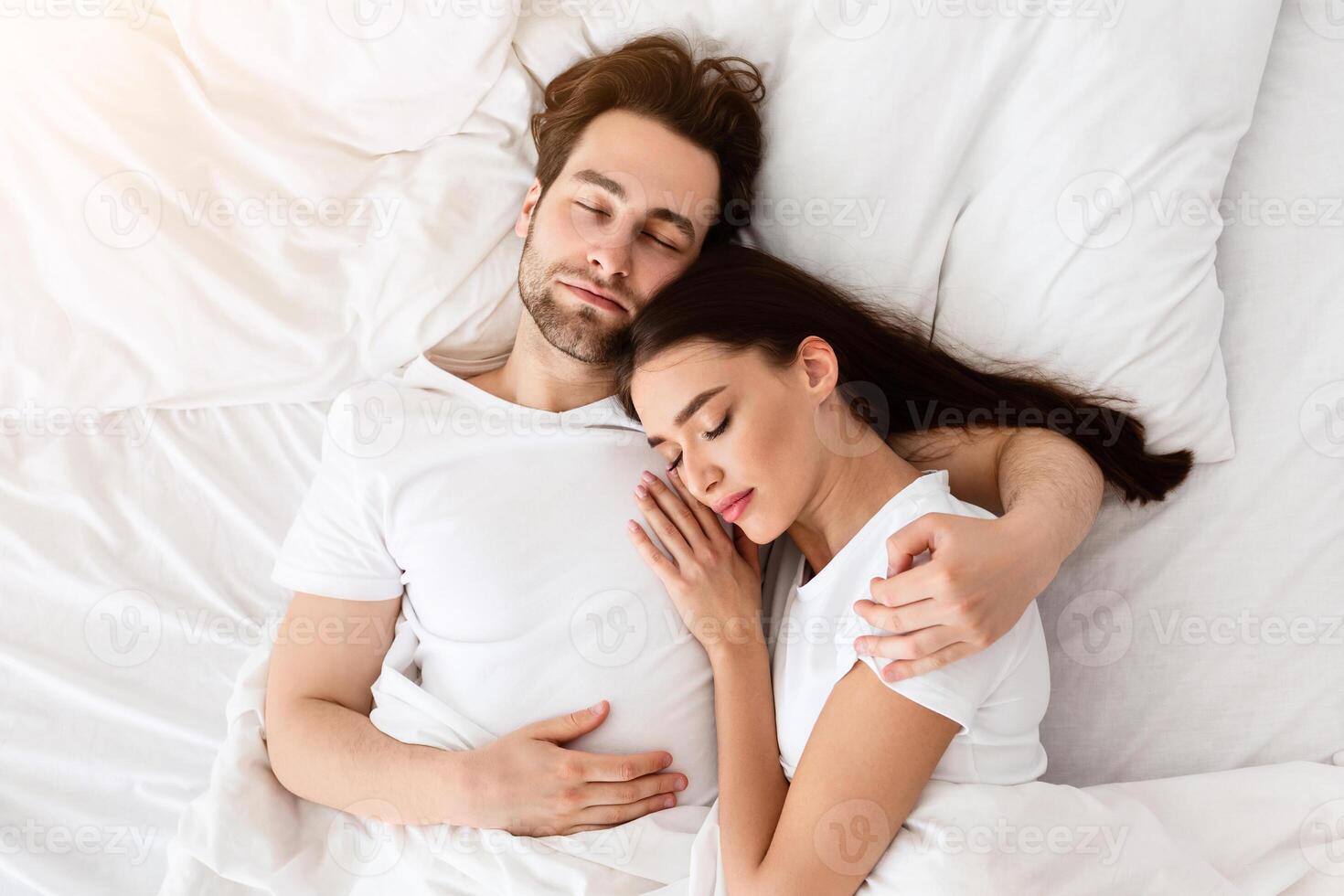 Married Couple Sleeping Together Embracing Lying In Comfortable Bed At Home At Night. Top View Shot Of Spouses Resting Peacefull Enjoying Nap In Comfortable Bedroom photo
