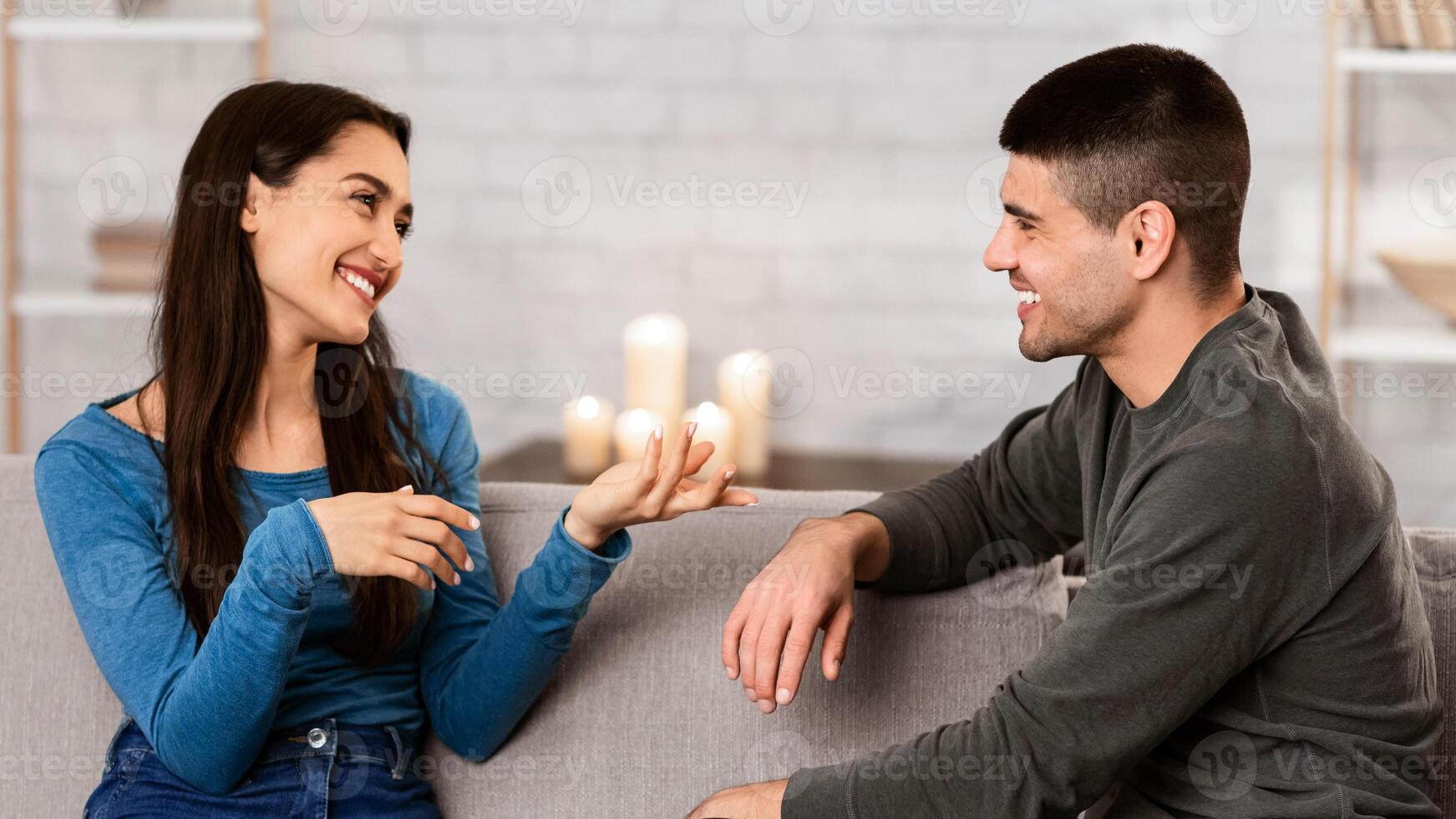 Beautiful couple talking, sitting on couch at home, have a nice conversation at their cozy apartment photo