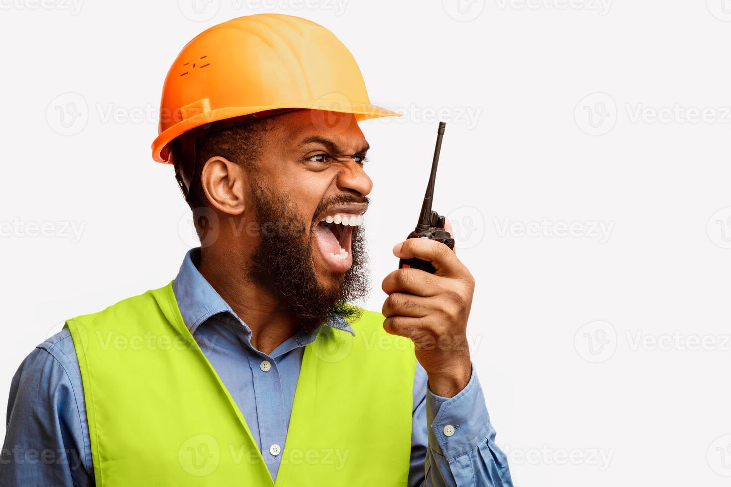Angry Black Construction Foreman Worker Shouting In Two-Way Radio At Builder Workers Over White Background. Studio Shot photo