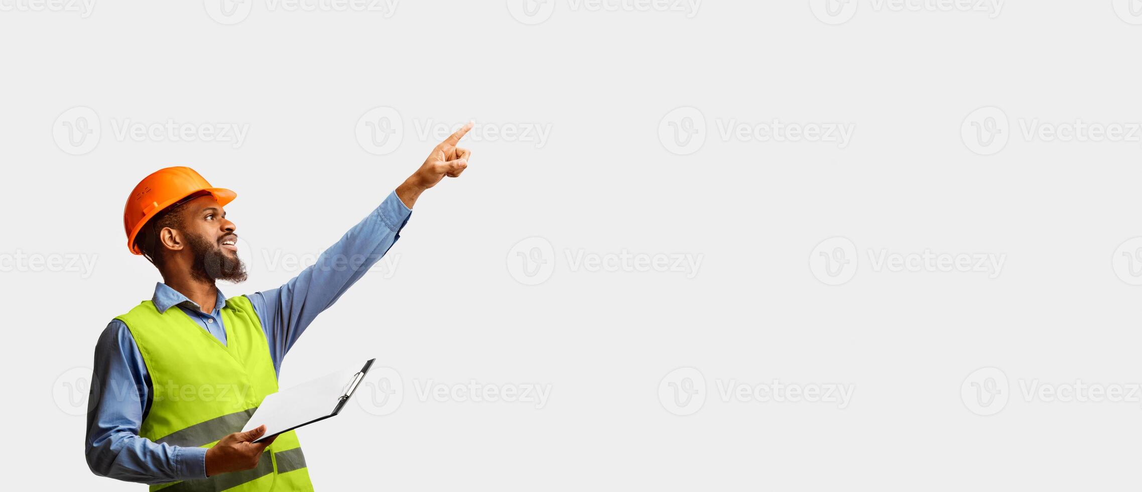 Black Architect Working On Construction Site Pointing Finger Holding Folder With Building Project Standing On White Studio Background. photo