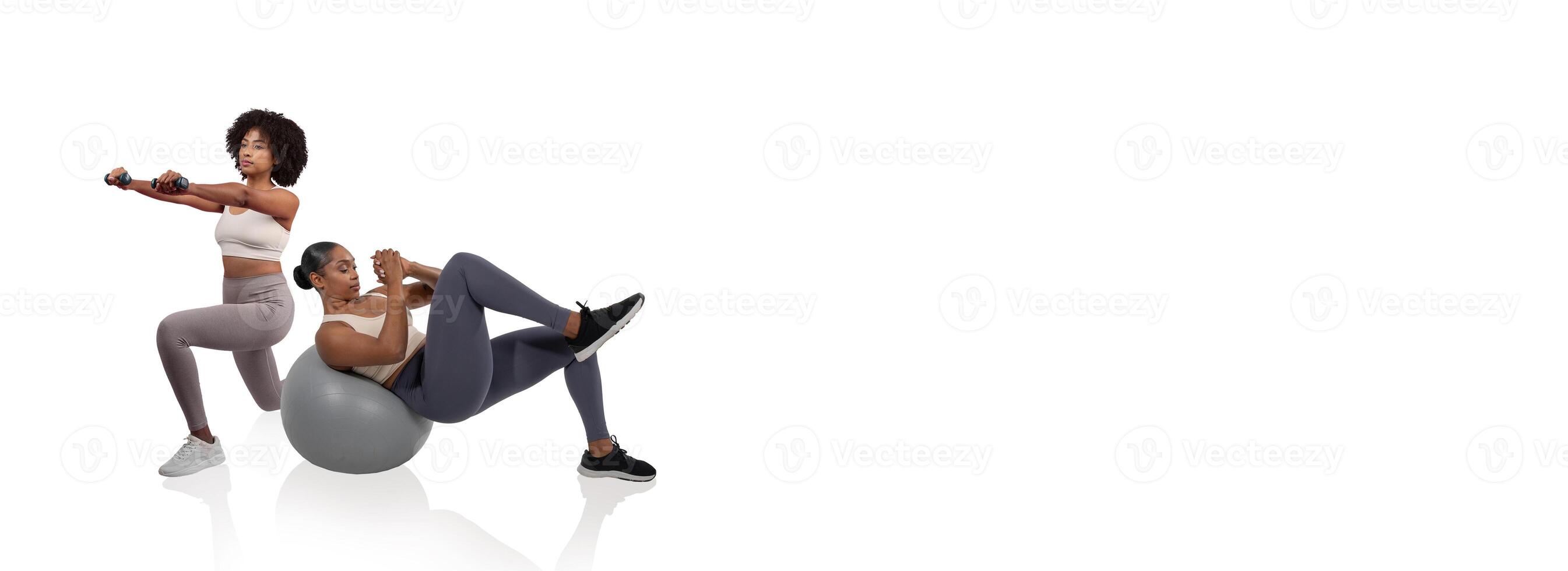 Two women are engaged in strength training inside a bright fitness studio, one using weights while seated on a stability ball, and the other performing an exercise in a squatting position. photo