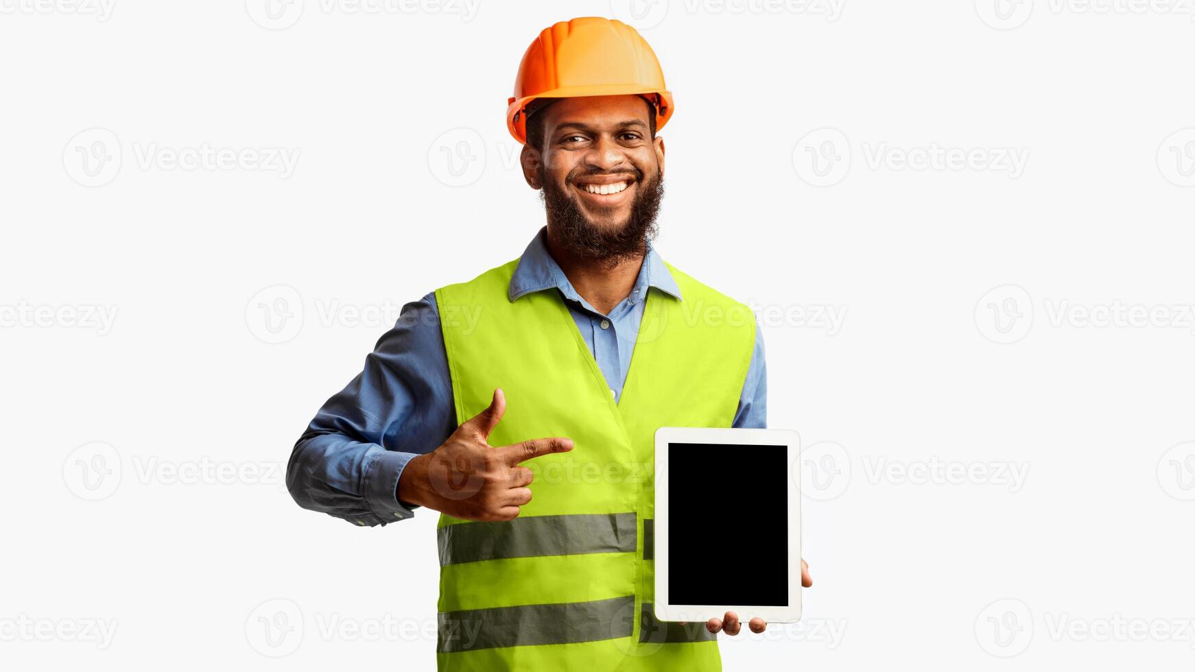 Builder Worker Showing Digital Tablet Empty Screen Pointing Finger Standing Over White Background. Panorama, Studio Shot photo