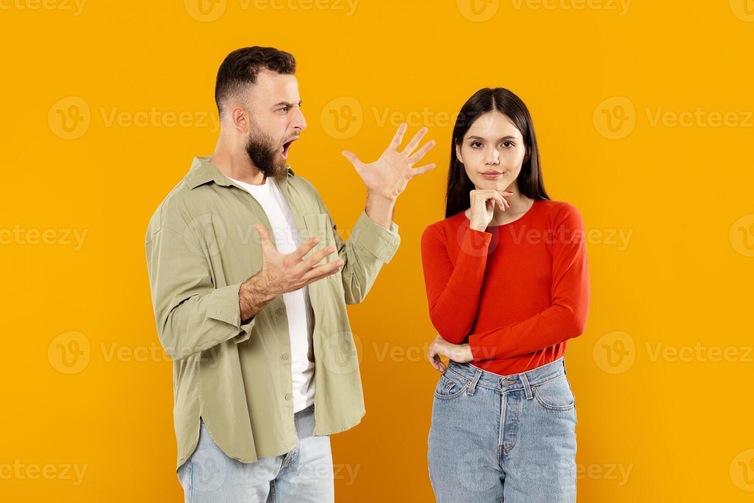 A young couple stands together, with the man expressing frustration through gestures while the woman appears contemplative. They are isolated, highlighting their emotional exchange. photo