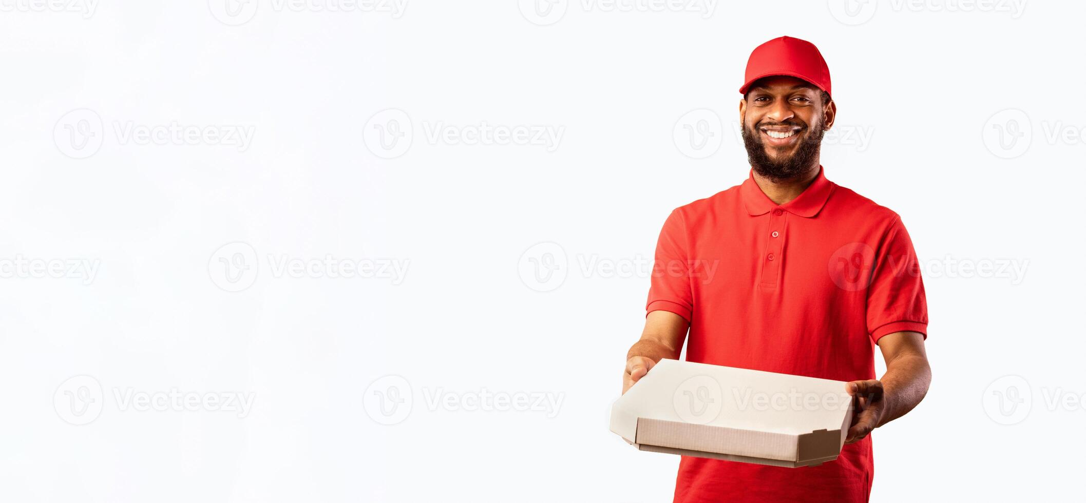 African Courier Guy Delivering Pizza Box Standing In Studio On Yellow Background. Pizzeria Delivery Service. photo