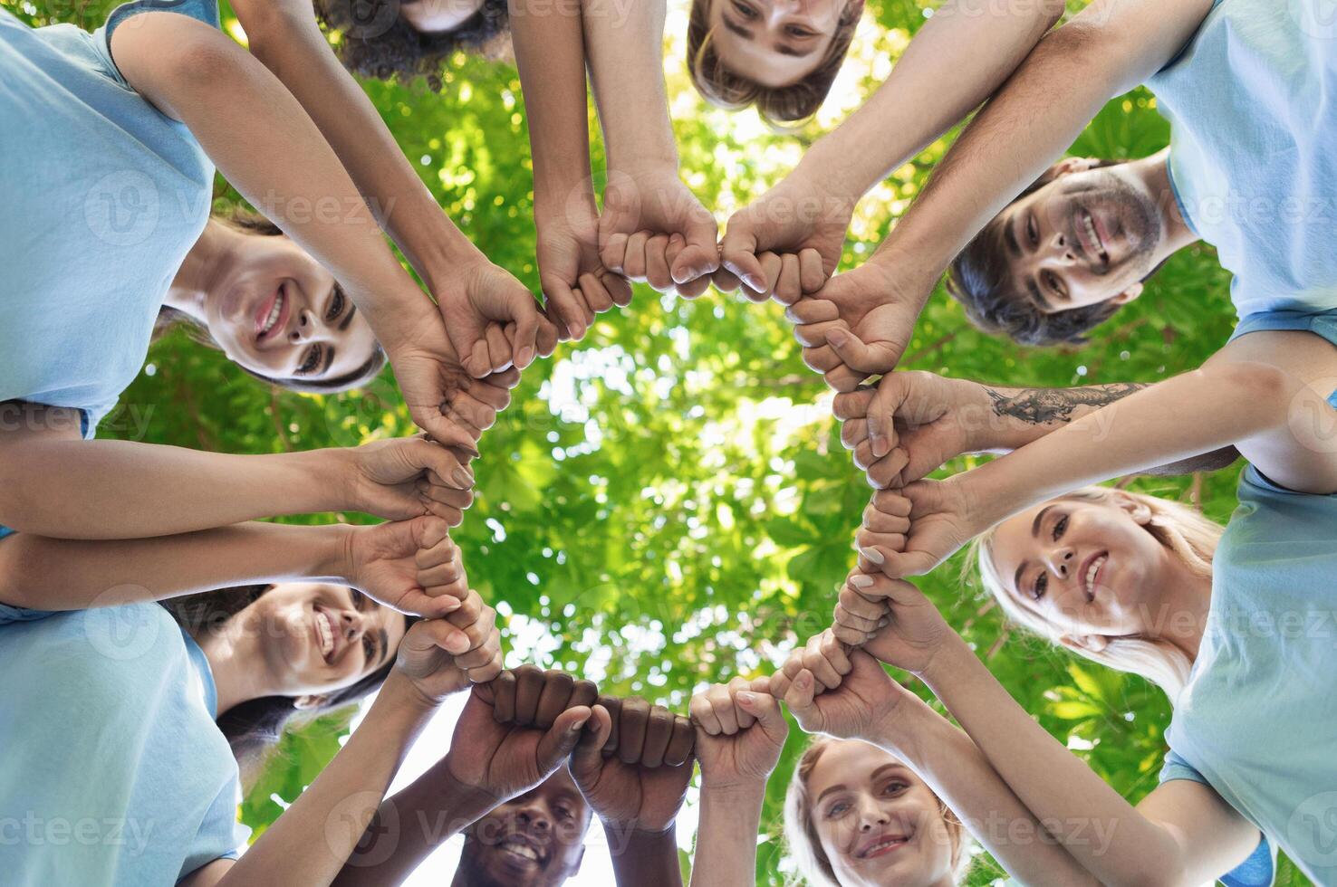 Happy volunteers fist bump together, standing in park and making circle, unity and collaboration concept, copy space photo