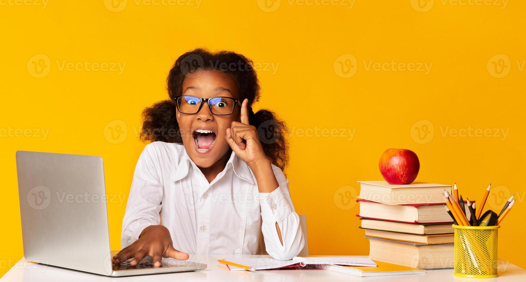 Idea Concept. Excited Afro School Girl Doing Homework At Laptop Raising Hand Pointing Finger Up Over Yellow Background In Studio. Panorama photo