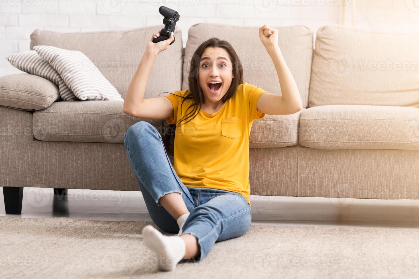 Self isolation hobbies. Young girl with joystick feeling happy for winning game at home photo