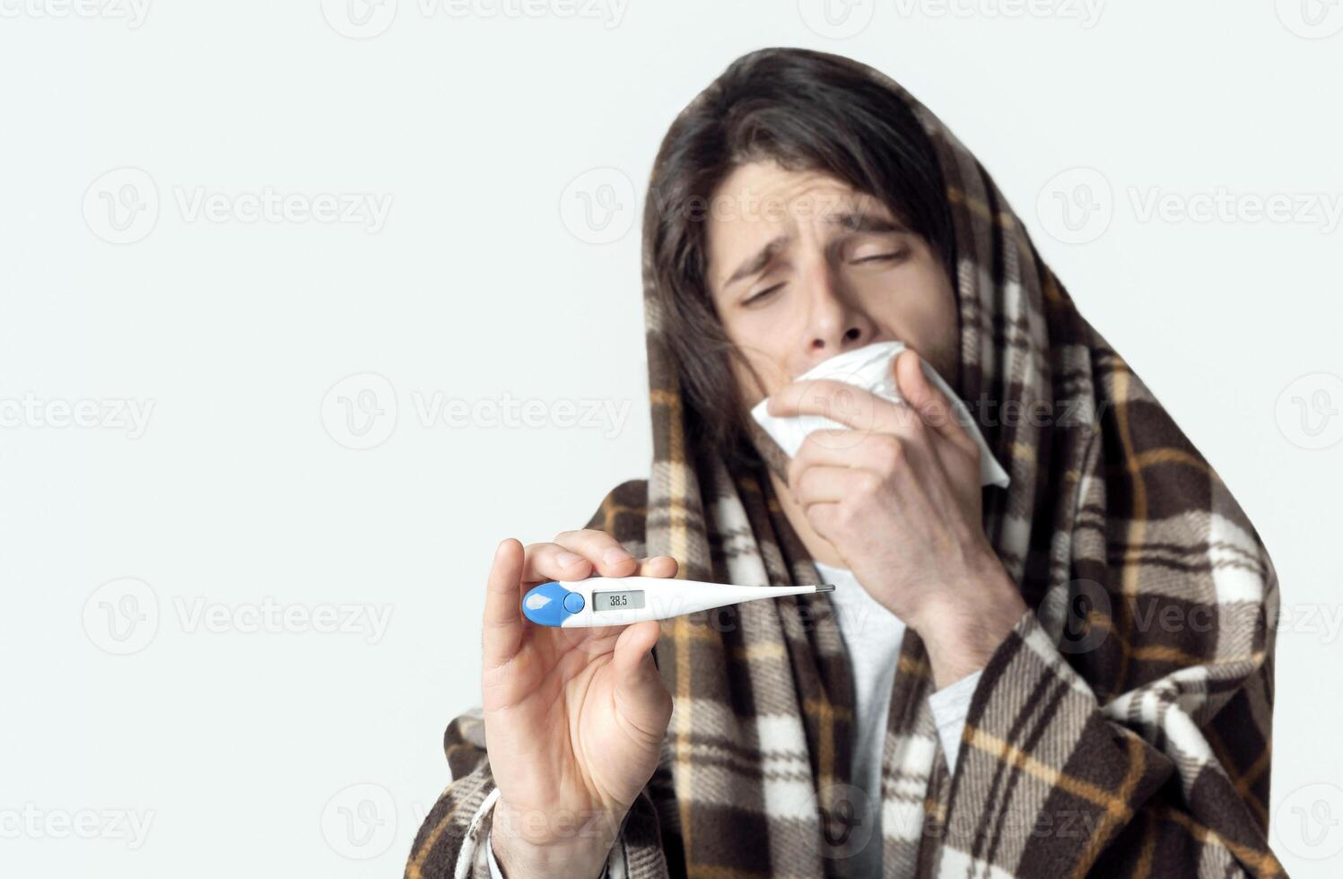 Man in plaid, covers mouth with napkin and shows thermometer, free space photo