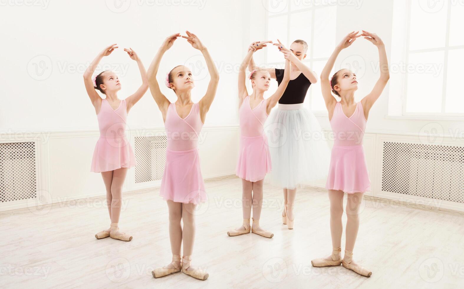 Young ballet teacher and students ballerinas in dance class. Girls are engaged in choreography in the ballet school. photo
