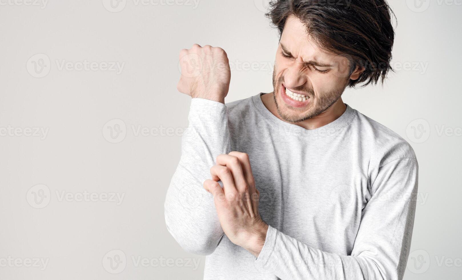 Skin irritation and itching. Man expression of pain, suffers from allergies or insect bites, panorama, cropped, studio shot photo