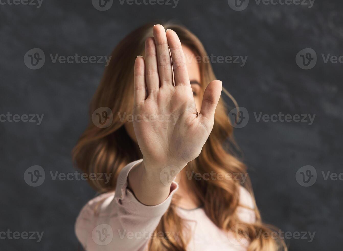 Woman showing no with her hand. Stop sign of discrimination or anti violence symbol, black studio background, copy space photo