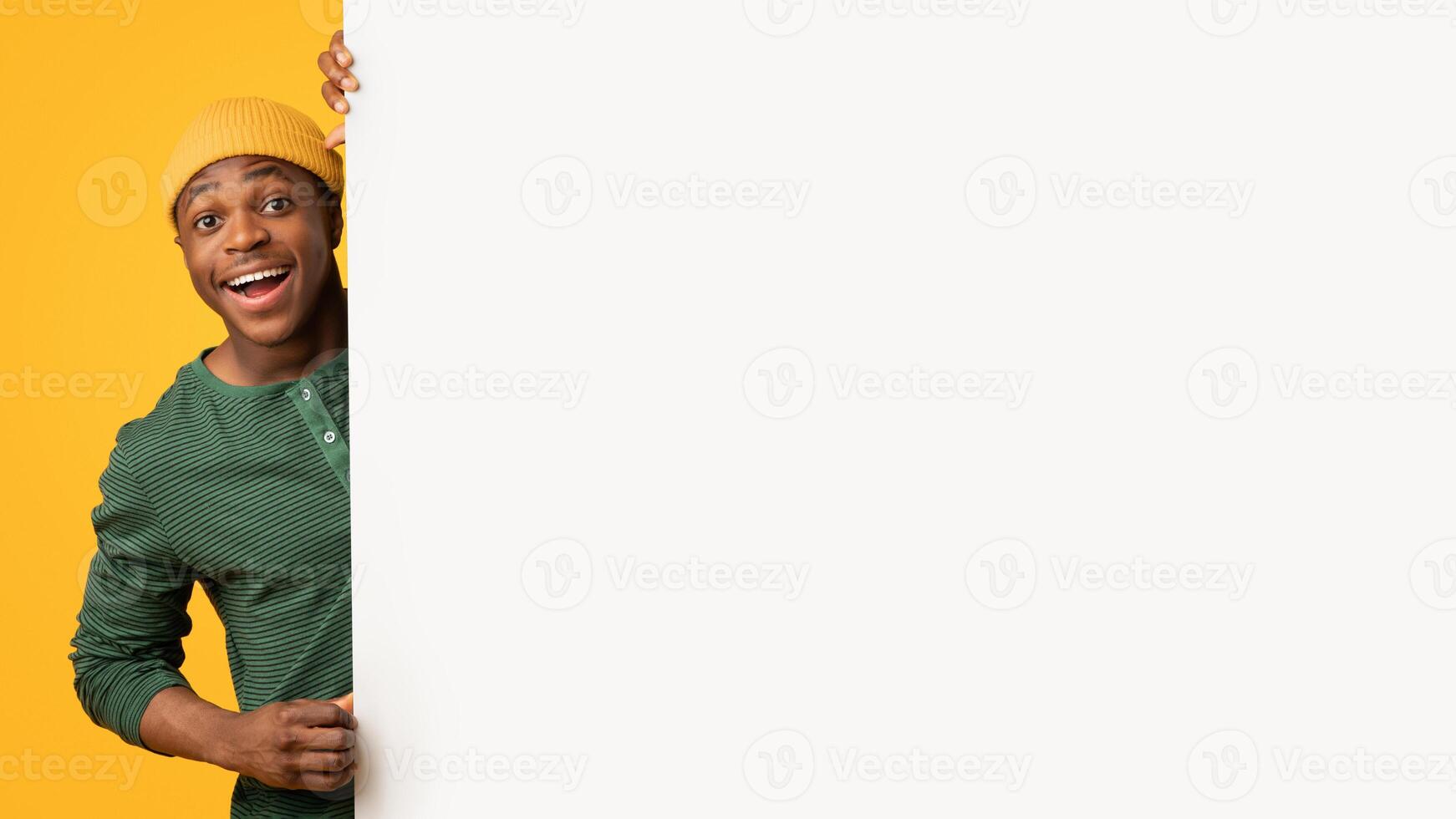 Cool Offer. Excited Funny Black Man Holding Blank White Advertisement Board, Cheerful African American Hipster Guy Demonstrating Big Placard With Free Copy Space For Your Design, Yellow Background photo