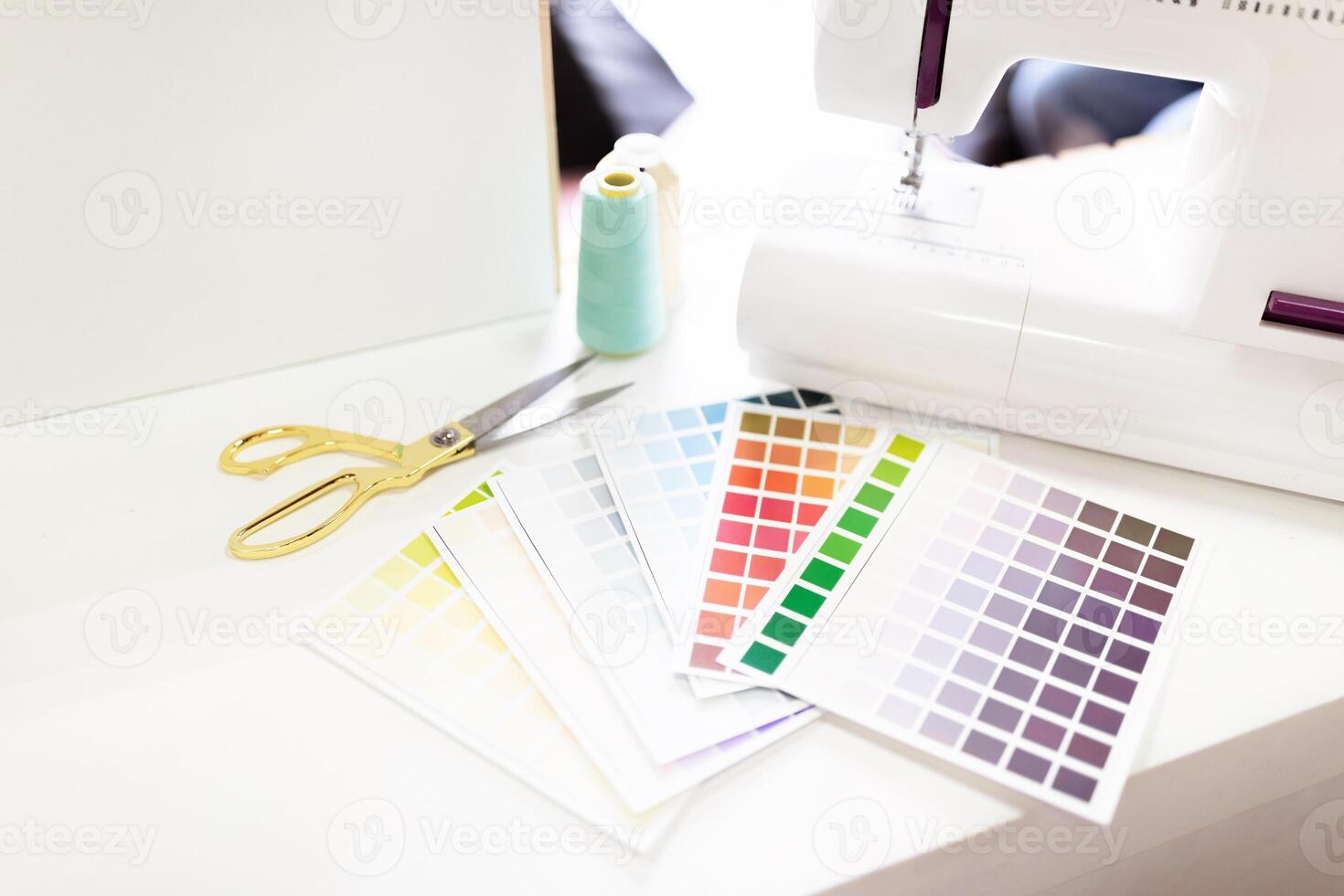 Scissors, fabric swatches, and a sewing machine are neatly organized on designer workspace. photo