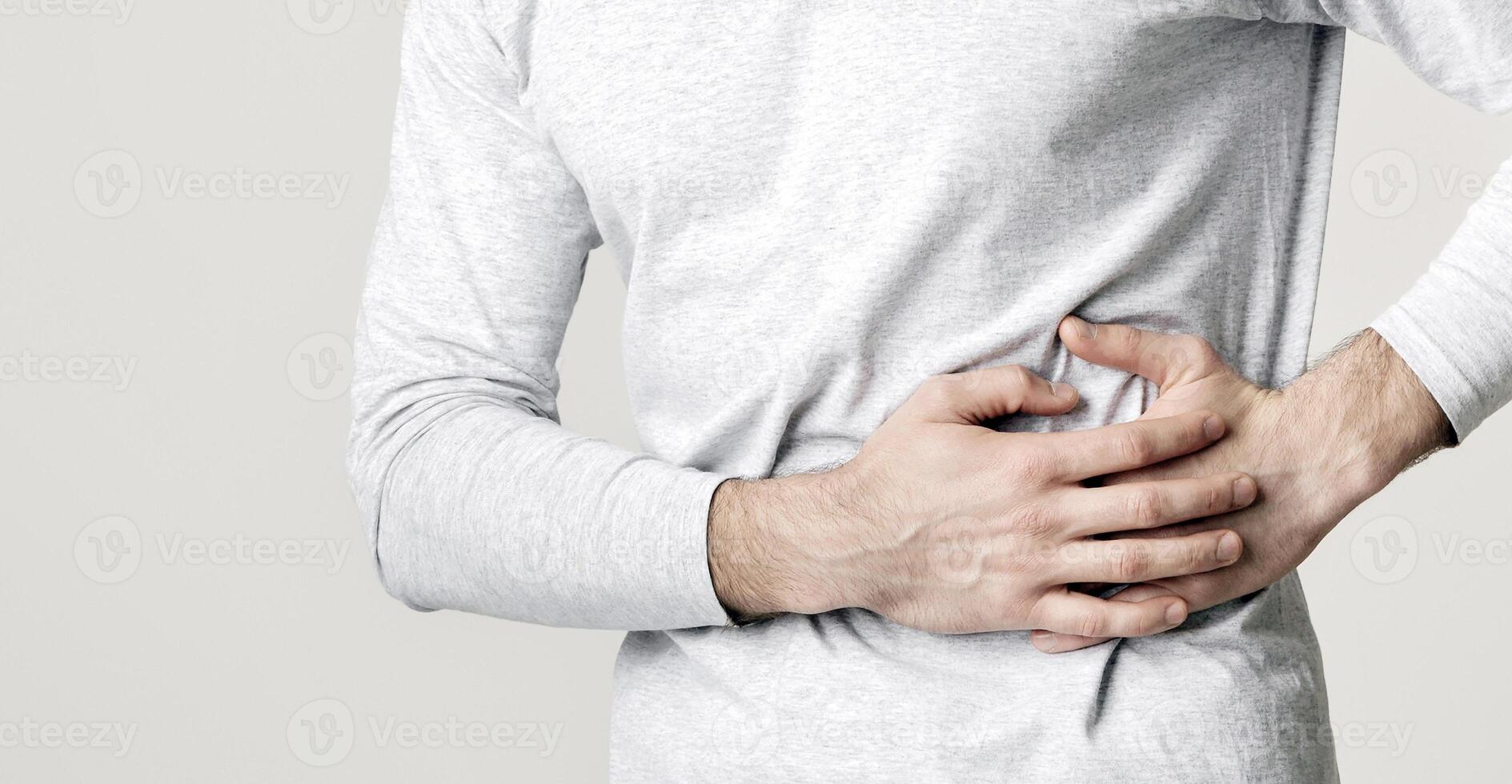 Liver pain. Guy holds hands on his side with torment facial expression photo