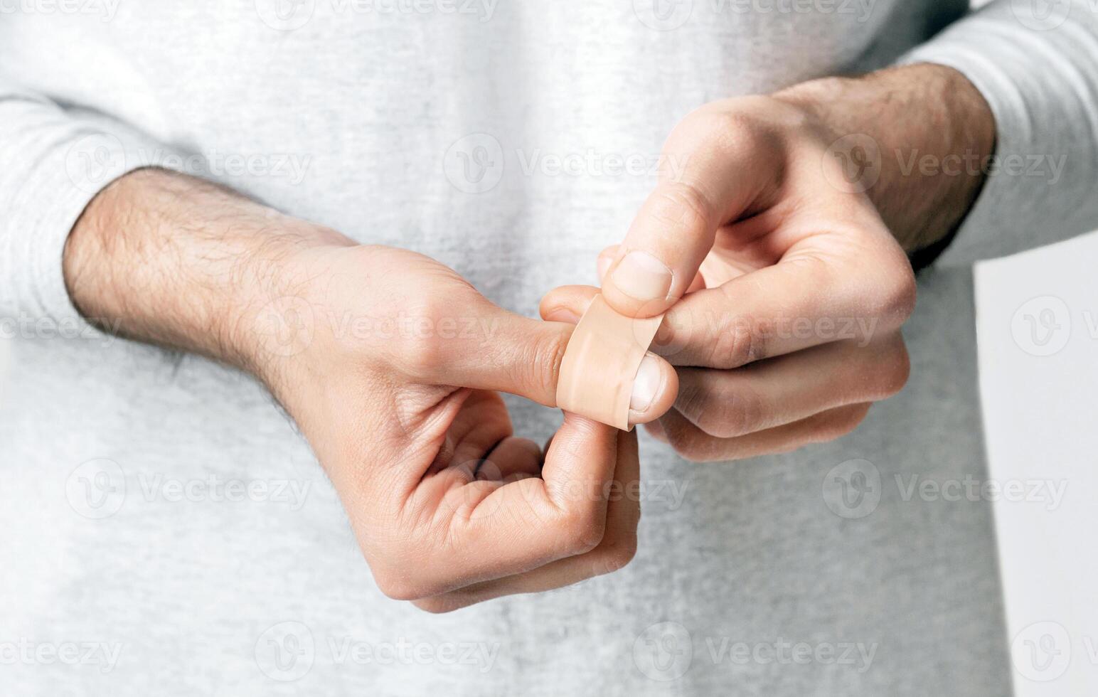 Wound, injury and pain. Man wraps his finger in band-aid, close up, panorama, cropped photo