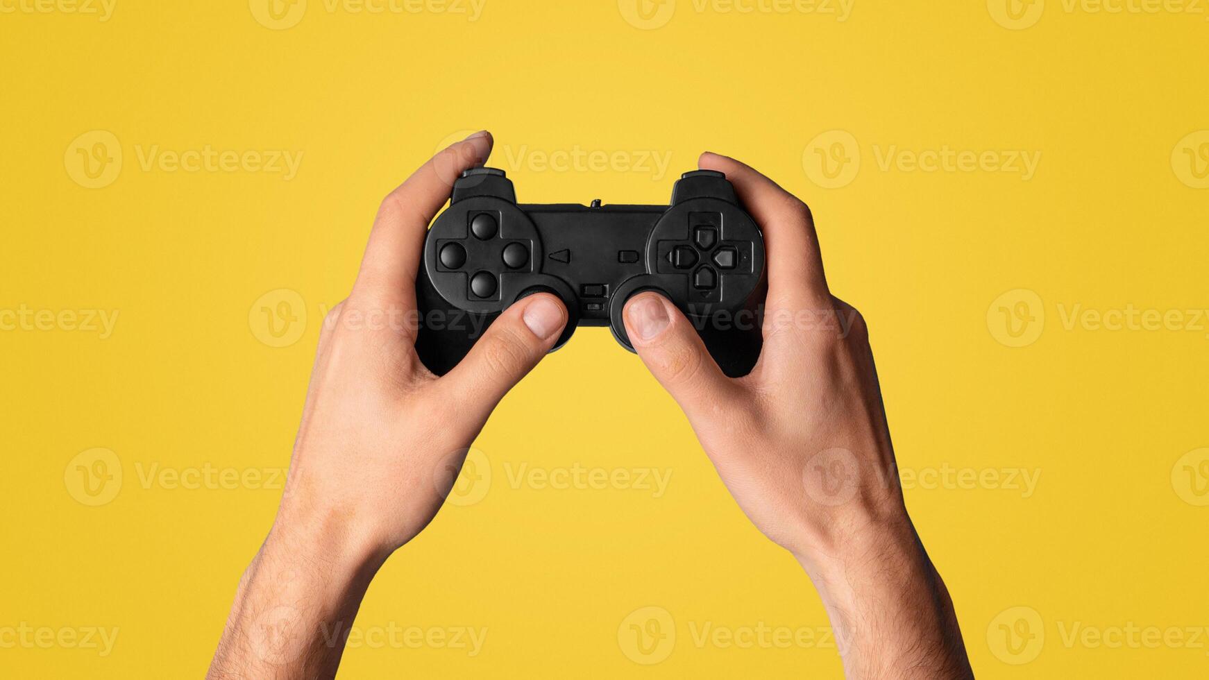 Lockdown activities. Millennial man holding game controller on blue background, closeup view. Panorama photo