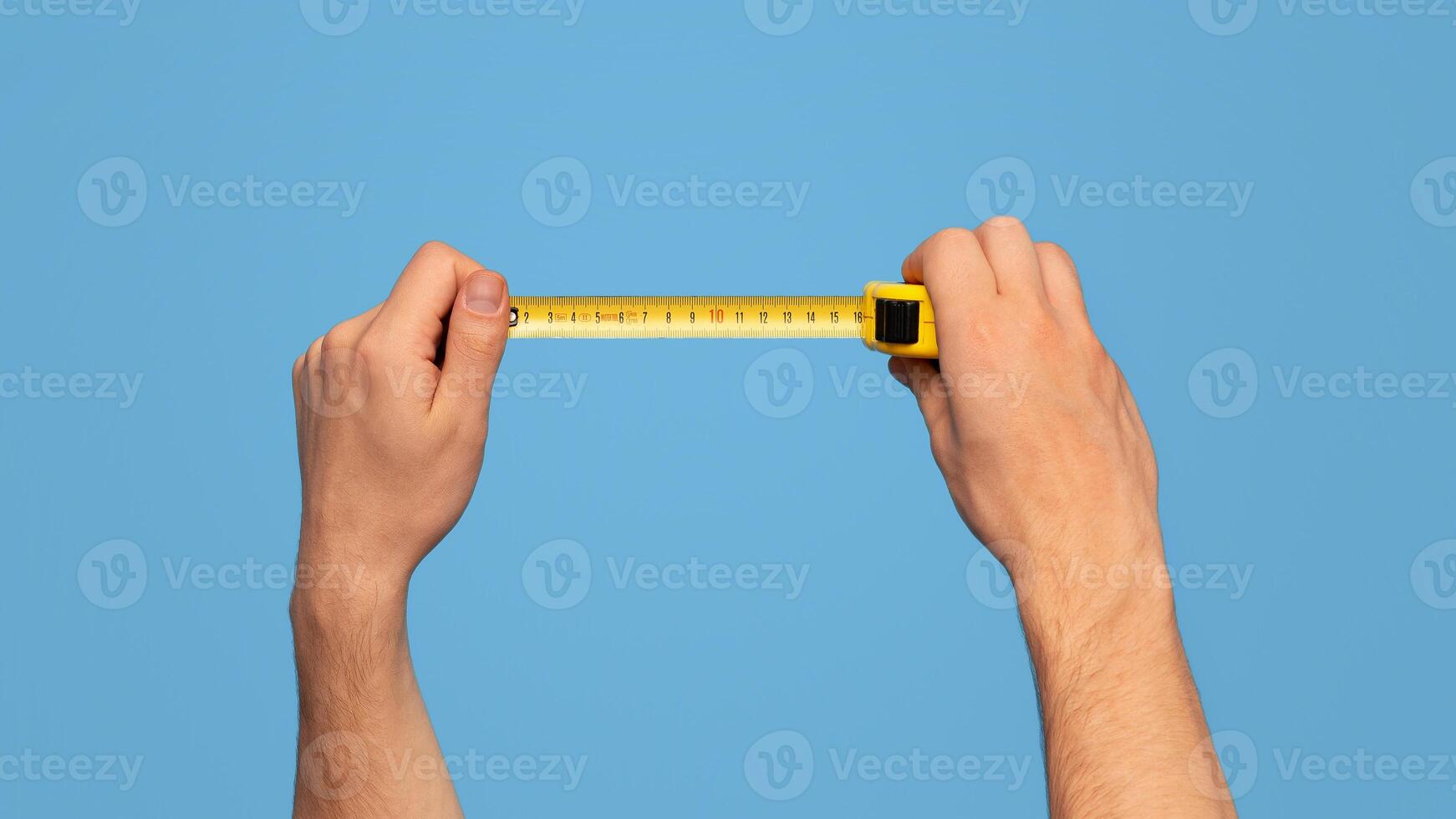 Handyman holding tape measure on blue background, closeup view. Panorama photo