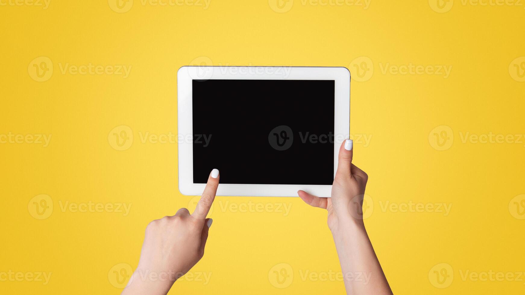 Millennial woman touching empty screen of tablet device on light background, close up. Space for design photo