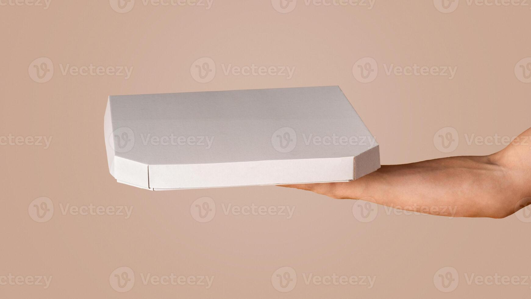 Unrecognizable delivery man holding box with takeaway pizza on orange background, mockup for your design. Panorama photo