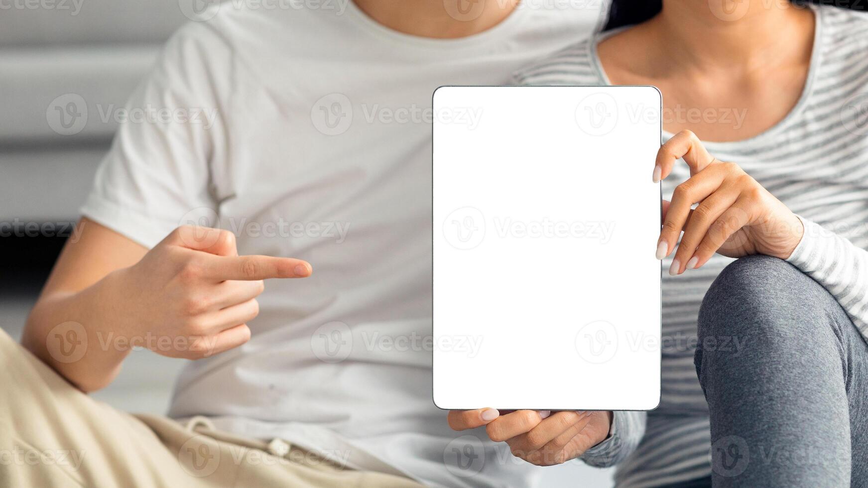 Closeup of unrecognizable asian couple holding digital tablet with blank screen, recommending nice fitness mobile application. Cropped of pad with empty screen in chinese man and woman hands, mockup photo
