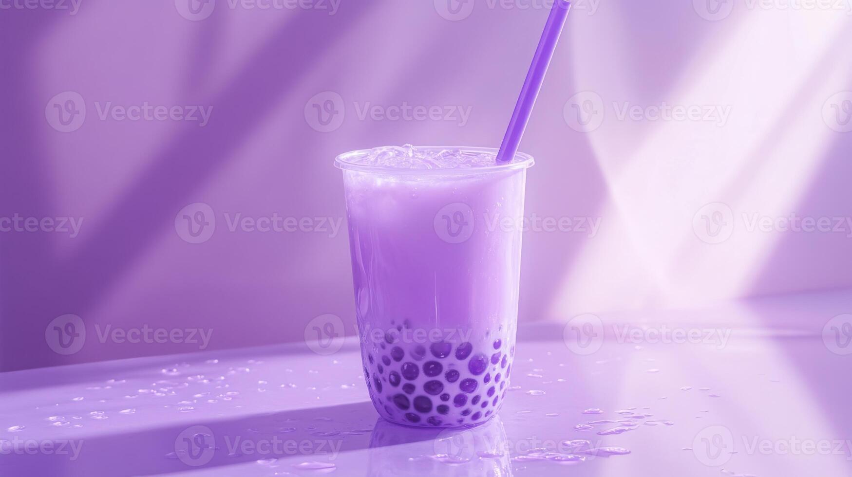 A clear cup filled with colorful purple bubble tea rests on a shiny surface, showcasing round tapioca pearls at the bottom. photo