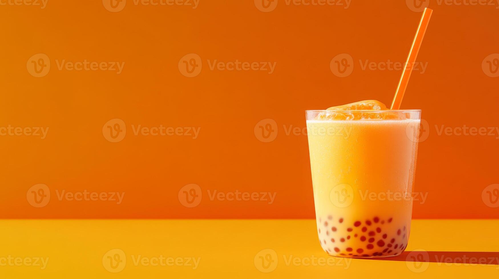 A transparent glass filled with smooth orange bubble tea featuring small tapioca pearls sits against an eye-catching orange backdrop, accompanied by a bright orange straw for sipping. photo