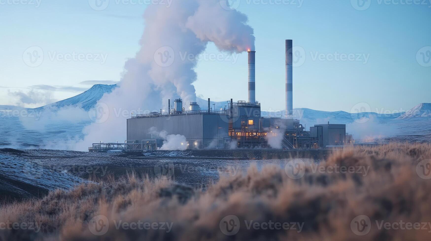 Industrial facility emitting steam, set against a mountainous landscape in a cold environment. photo