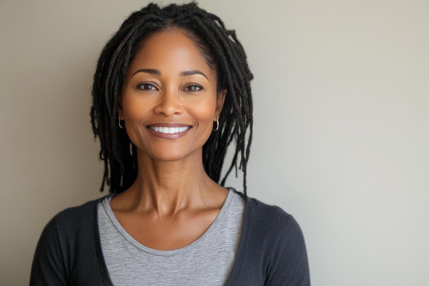Portrait of a woman with long dreadlocks smiling against a light background photo