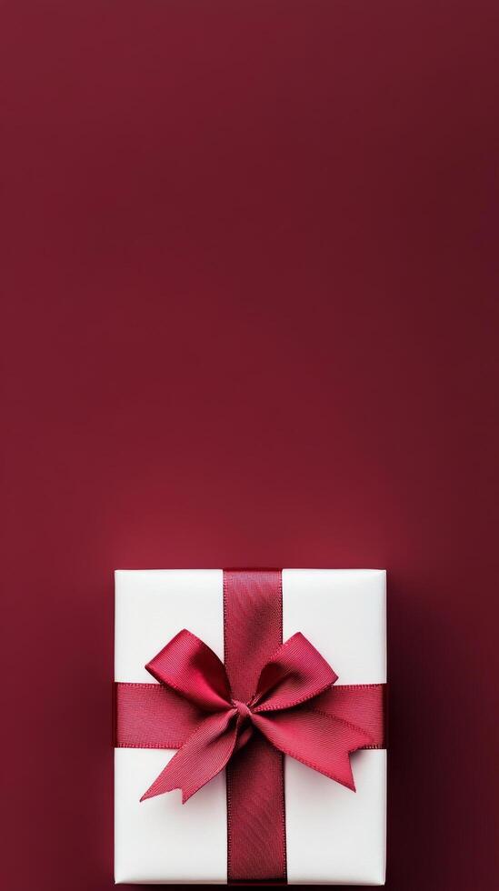 Elegant gift box with red ribbon on a rich maroon background for special occasions photo