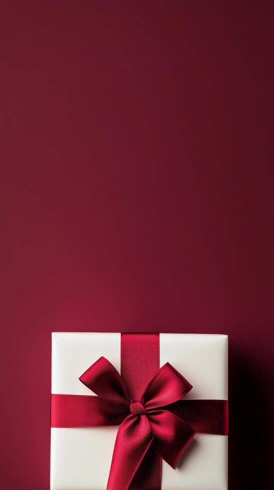 Elegant gift box with red ribbon on a rich maroon background for special occasions photo