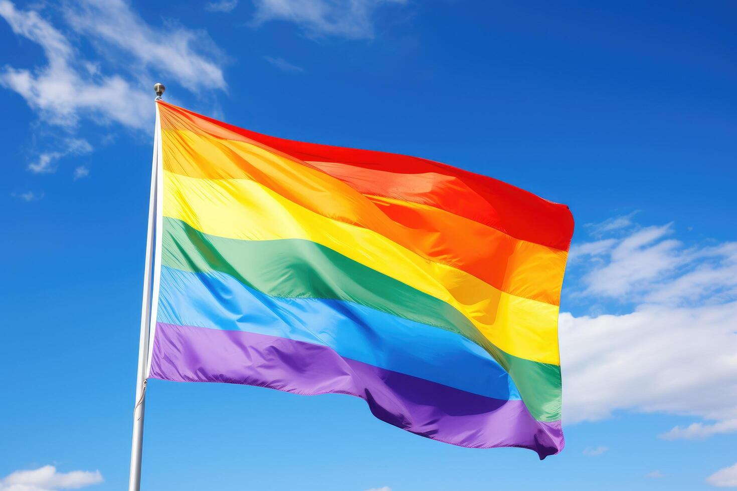 Vibrant rainbow flag waving against blue sky photo