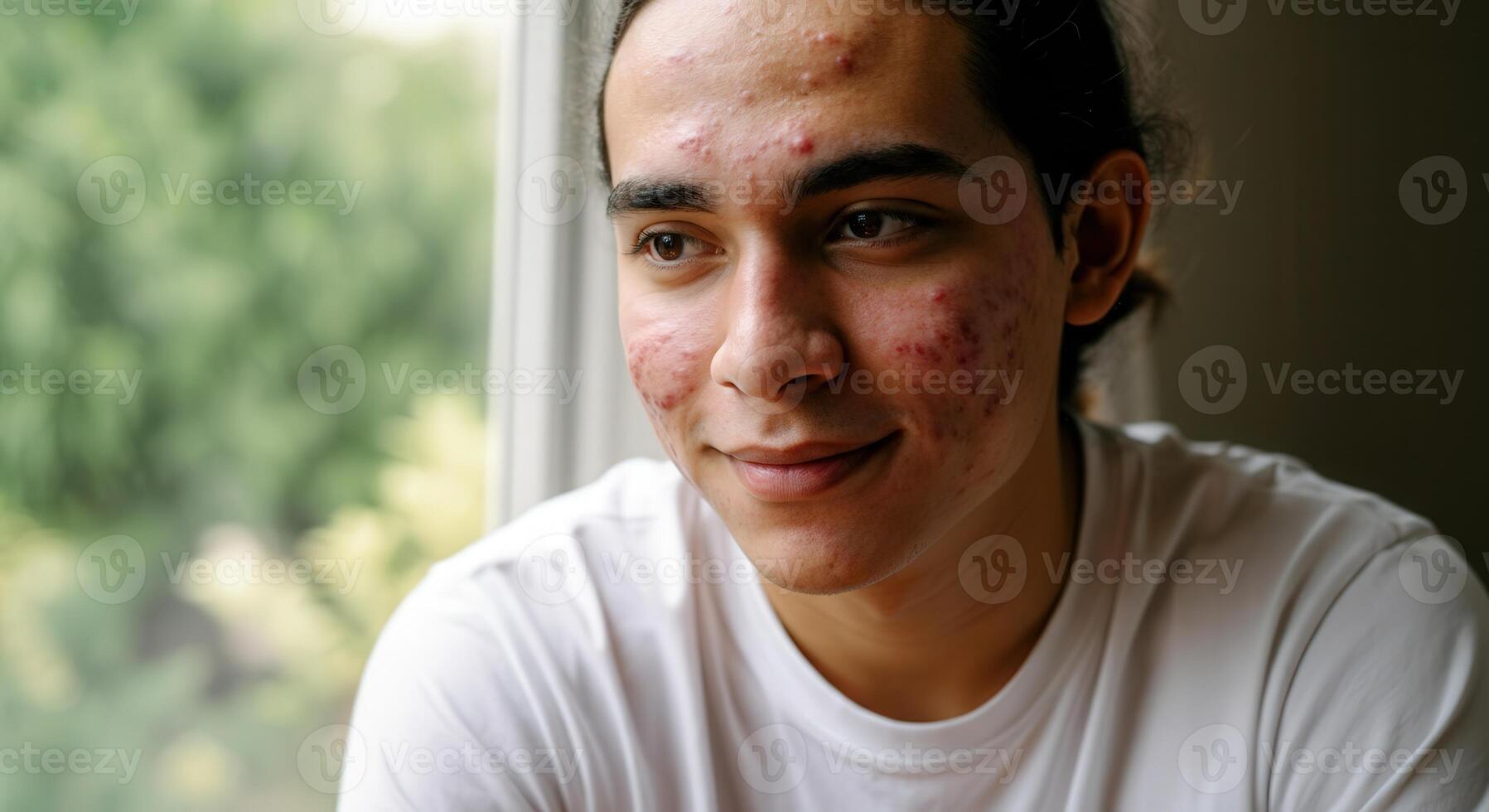 Portrait of a young man with natural skin texture and a contemplative expression by a window photo