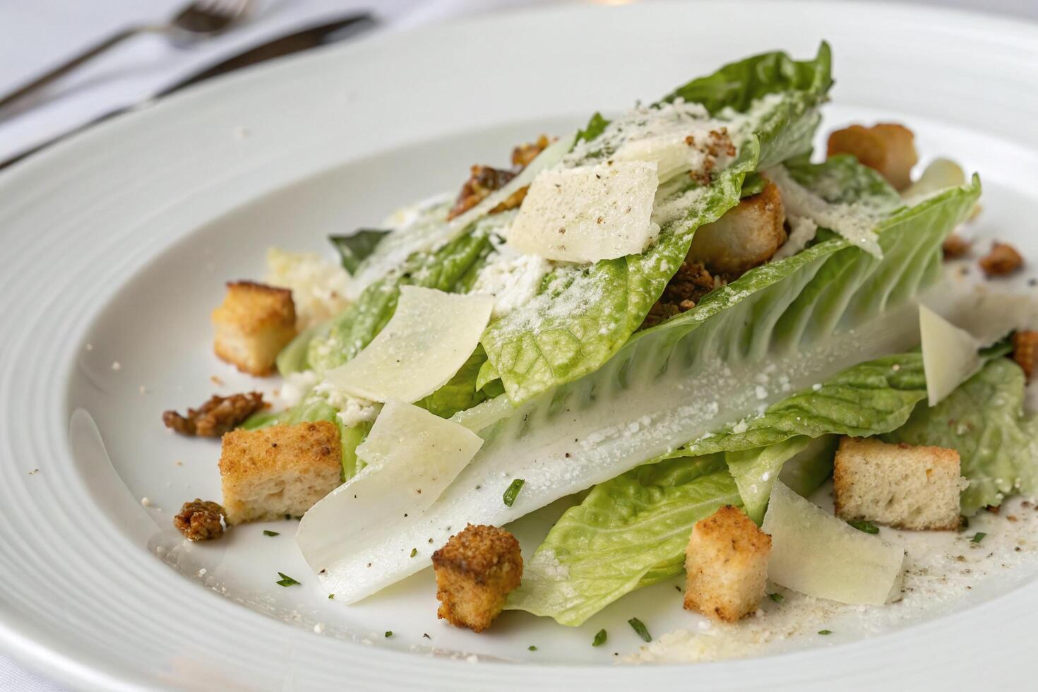 Fresh Caesar Salad with Parmesan Cheese and Croutons on a White Plate photo