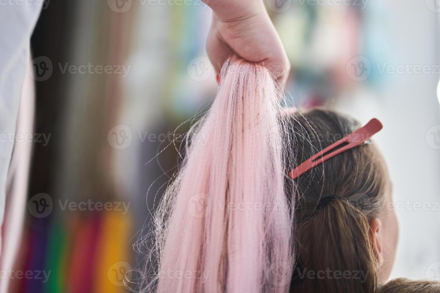 Preparation of a pink kanekalon, for weaving into the hair of a child. The hands of the master hold the material. With space to copy photo