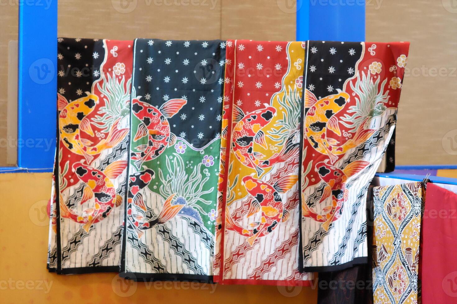 An array of Indonesian batik shirts and batik cloth hangs on the racks, displaying a variety of patterns and colors. photo