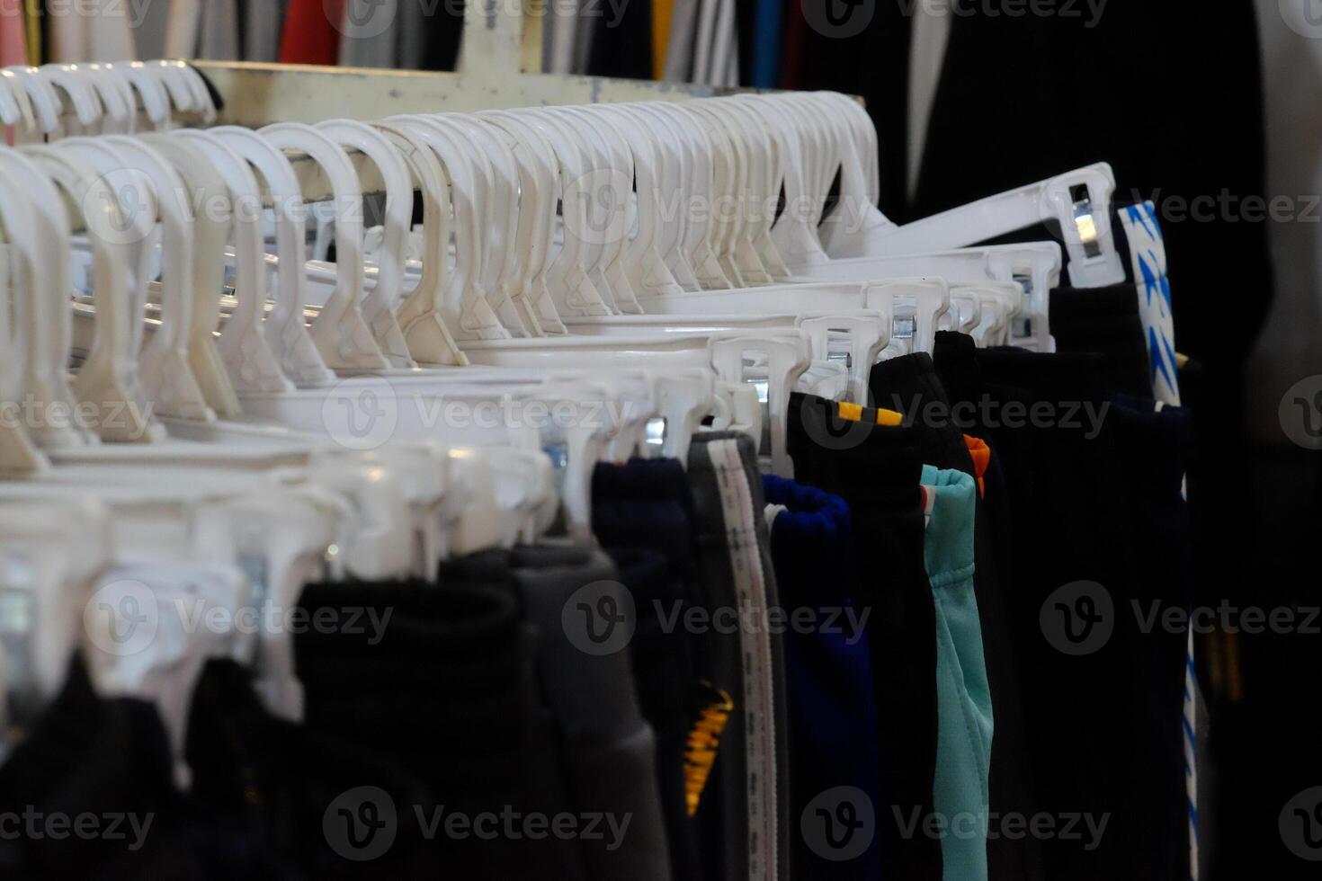 Thrifting's vibrant collection of sweaters, shirts, hoodies, trousers and knitted t-shirts are elegantly displayed on wooden hangers, featuring a variety of colors and textures. photo