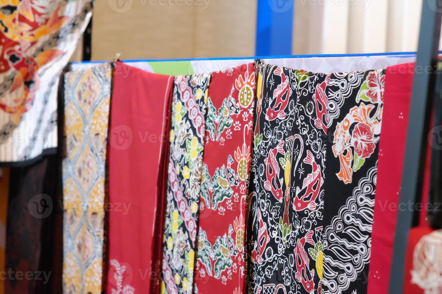 An array of Indonesian batik shirts and batik cloth hangs on the racks, displaying a variety of patterns and colors. photo