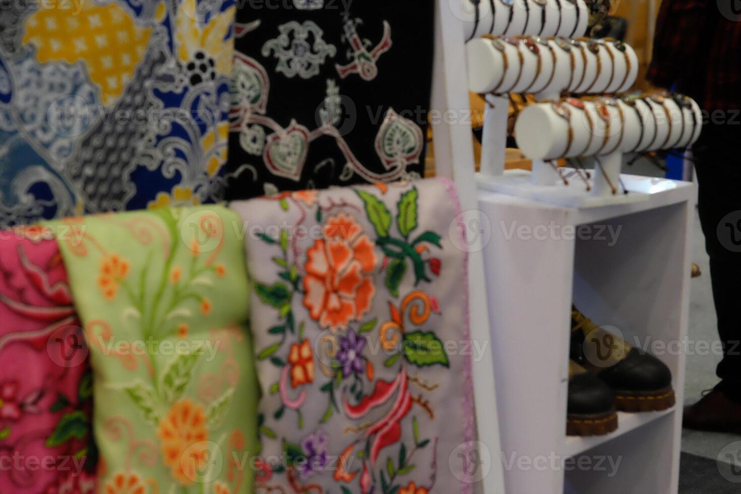 An array of Indonesian batik shirts and batik cloth hangs on the racks, displaying a variety of patterns and colors. photo