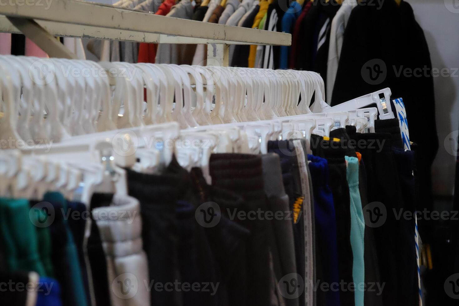 Thrifting's vibrant collection of sweaters, shirts, hoodies, trousers and knitted t-shirts are elegantly displayed on wooden hangers, featuring a variety of colors and textures. photo