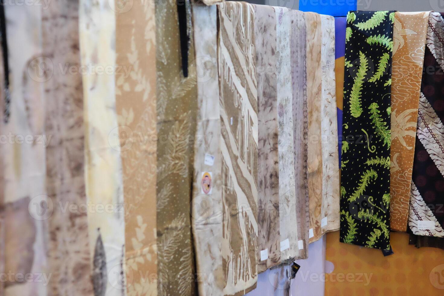 An array of Indonesian batik shirts and batik cloth hangs on the racks, displaying a variety of patterns and colors. photo