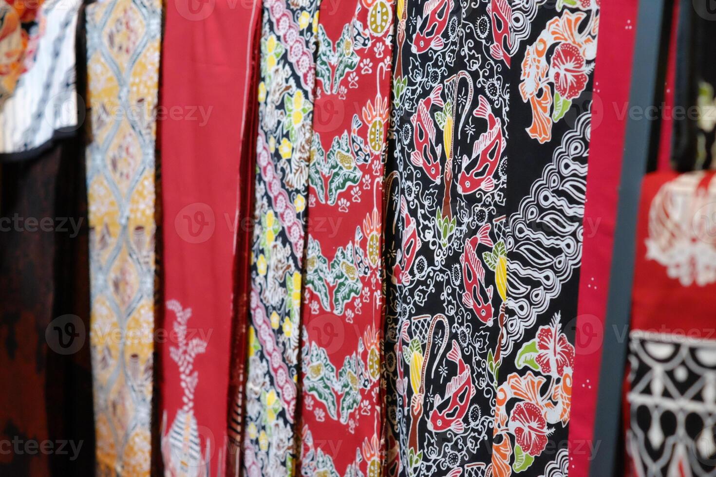 An array of Indonesian batik shirts and batik cloth hangs on the racks, displaying a variety of patterns and colors. photo