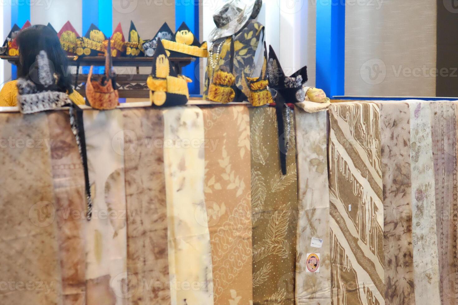 An array of Indonesian batik shirts and batik cloth hangs on the racks, displaying a variety of patterns and colors. photo