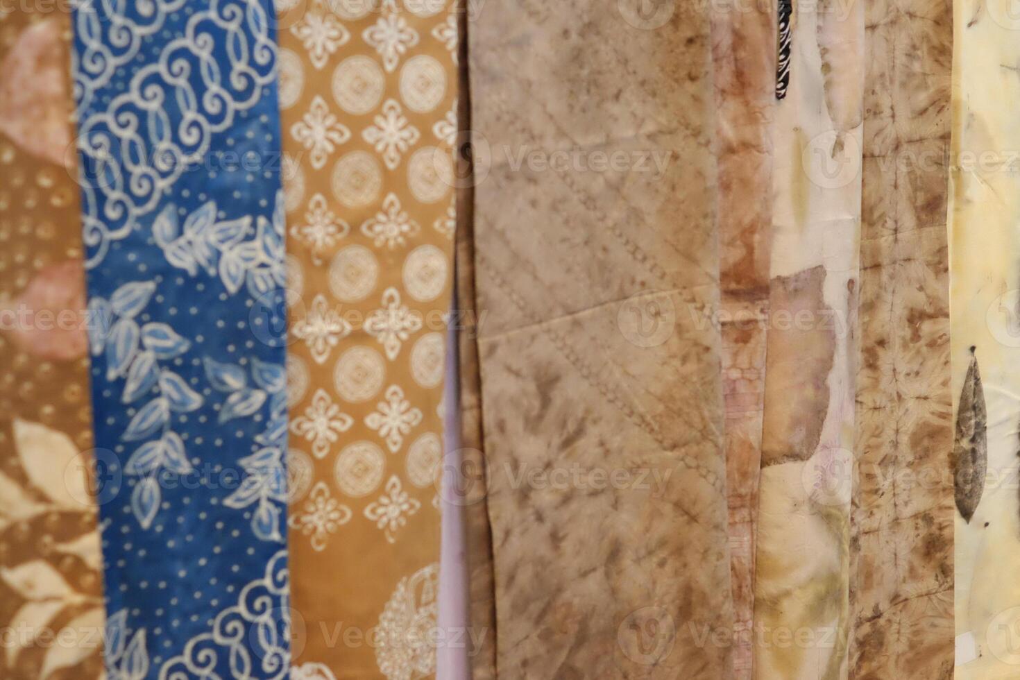 An array of Indonesian batik shirts and batik cloth hangs on the racks, displaying a variety of patterns and colors. photo