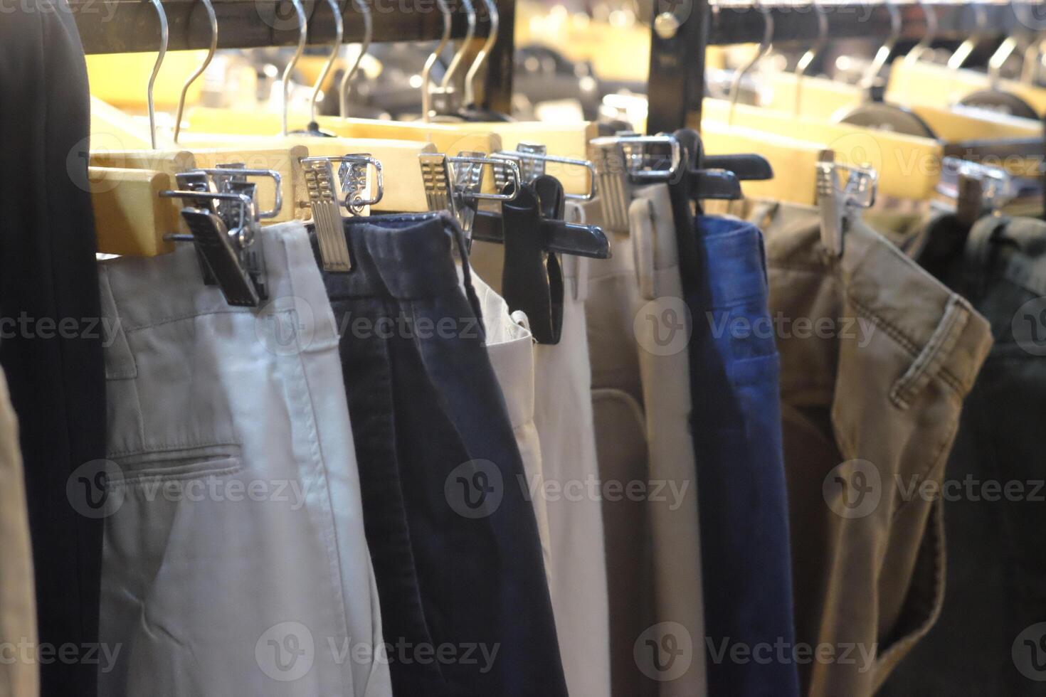 Thrifting's vibrant collection of sweaters, shirts, hoodies, trousers and knitted t-shirts are elegantly displayed on wooden hangers, featuring a variety of colors and textures. photo