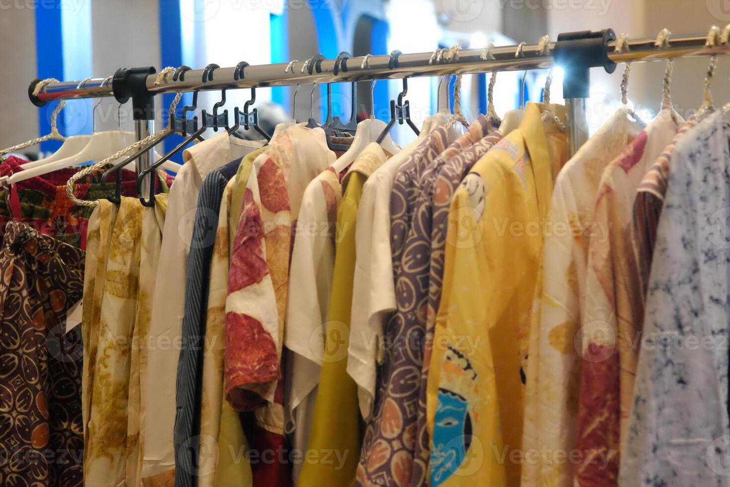 An array of Indonesian batik shirts and batik cloth hangs on the racks, displaying a variety of patterns and colors. photo